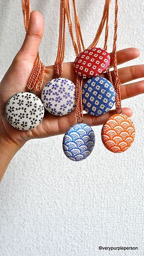 a person holding five different colored stones in their hand, all with designs on them