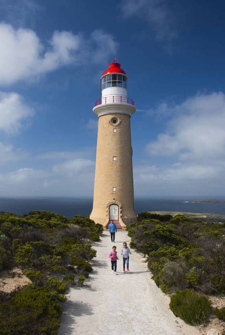 two people walking up a path towards a light house