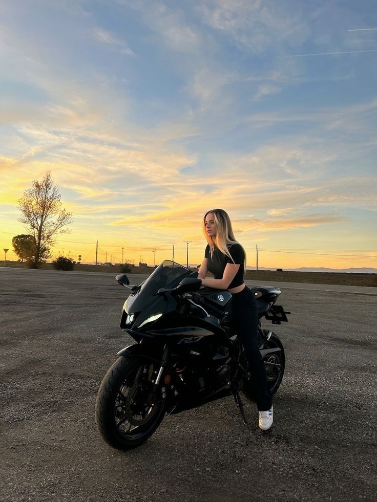 a woman sitting on top of a motorcycle in the middle of an empty parking lot