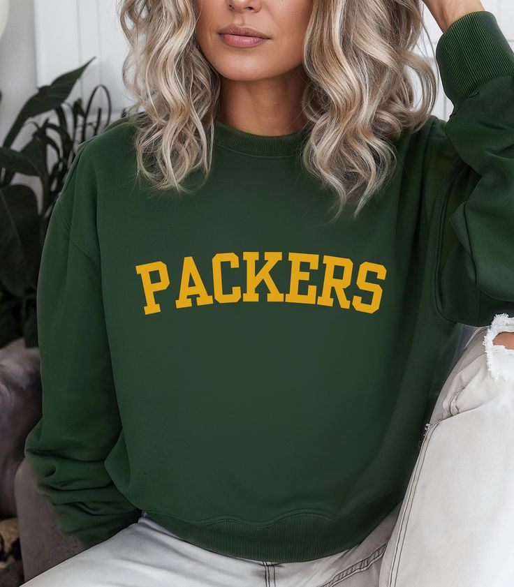 Show your unwavering support for the Green Bay Packers with our standout Crewneck Sweatshirt. Featuring bold "PACKERS" lettering, this football sweatshirt is a must-have for any true fan. Its classic crewneck design offers a relaxed fit that's perfect for game days, whether you're cheering from the stands or watching from the comfort of your home. This sweatshirt effortlessly pairs with your favorite jeans or sweatpants, making it a versatile addition to your casual wardrobe. The striking Packer Green Bay Packers Outfits Woman, Fall Sports Fan Tops With Letter Print, Sports Fan Tops With Letter Print For Fall, Sports Fan Letter Print Tops For Fall, Fan Apparel Sweatshirt With Letter Print For Game Day, Casual Sweatshirt With Text Print For Fans, Green Tops For Fall Sports Events, Game Day Green Sweatshirt With Team Spirit, Team-colored Sweatshirt With Letter Print For Game Day