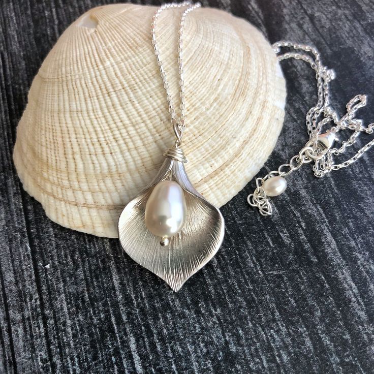 Shop Calla Lily Necklace Sterling Silver. Flower Pendant Pearl Necklace will add a perfect touch of flair to your outfit! It will make a great bridesmaid gift or gift for mom, daughter. You can wear it with your evening dress or favorite jeans. Calla lily necklace will make a great gift!  Your order will arrive in a nice pouch ready to be given. The pendant necklace is made from: - Rhodium plated calla lily pendant (26mm x 35mm) - White Swarovski teardrop pearl - Sterling silver diamond cut spar Bohemian Flower Necklaces For Weddings, Bohemian Wedding Necklaces With Flower Shape, Bohemian Flower Necklace For Weddings, Bohemian Wedding Necklace With Flower Shape, Bohemian Wedding Necklaces With Flower Charm, Bohemian Flower Pendant Necklace For Wedding, Elegant Petal-shaped Wedding Necklaces, Elegant Flower Necklace For Beach, Elegant Handmade Flower Necklace