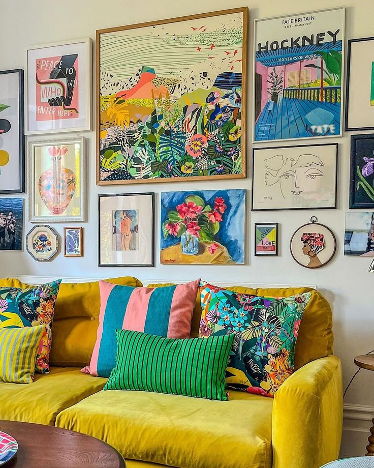 a living room filled with lots of colorful pillows and pictures on the wall above it