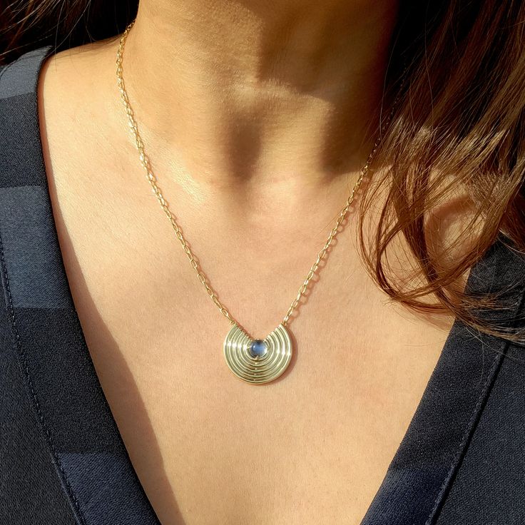 Basking in the glow of this ethereal moonstone necklace. Modern Round Cabochon Necklace, Modern Cabochon Necklace, Round Lapis Lazuli Necklace With Natural Stones, Lapis Lazuli Necklaces With Natural Stones, Lapis Lazuli Natural Stones Round Necklace, Modern Gemstone Round Necklace, Modern Round Gemstone Necklace, Oval Cabochon Brass Necklace, Gold Oval Pendant Necklace In Labradorite