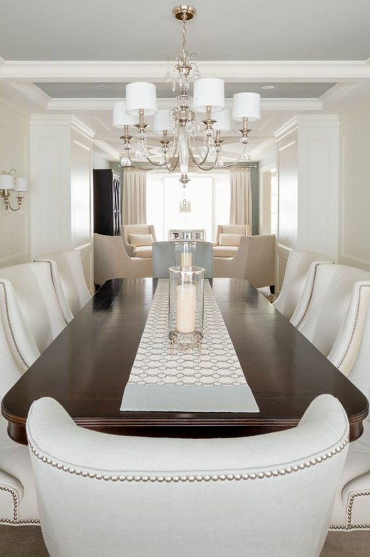 a dining room table with white chairs and a chandelier