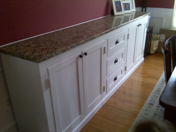 a kitchen with white cabinets and brown counter tops