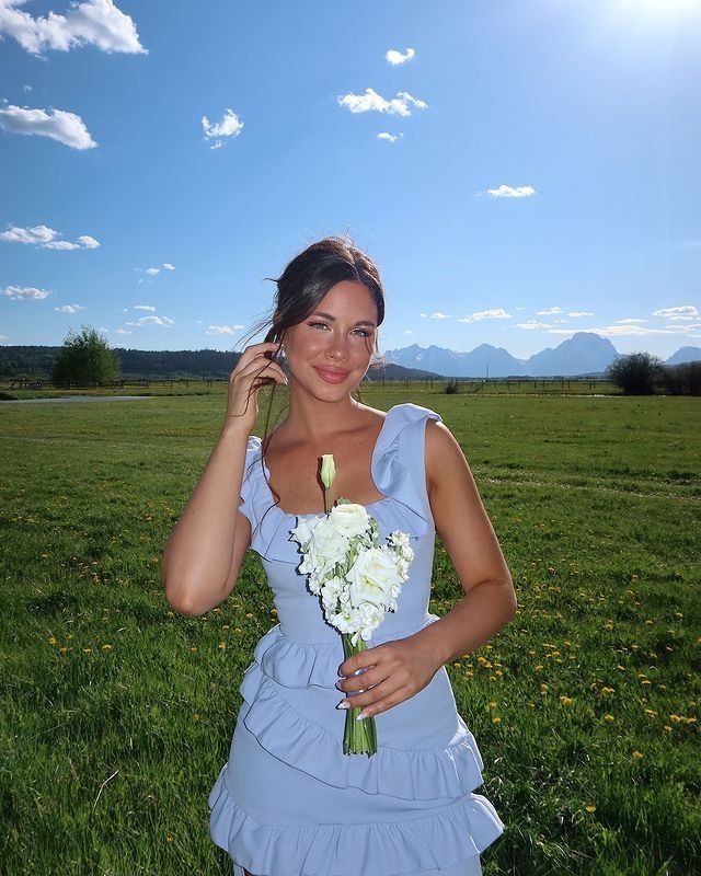 a beautiful young woman holding a bouquet of flowers in her hand while talking on the phone