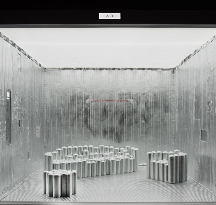 an empty room with several cylindrical objects in it's center, all lined up and facing the same direction