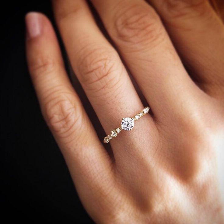 a woman's hand with a diamond ring on top of her finger and an engagement band