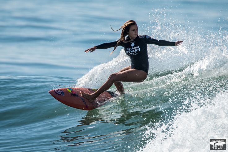 a woman riding a surfboard on top of a wave in the ocean with her arms out