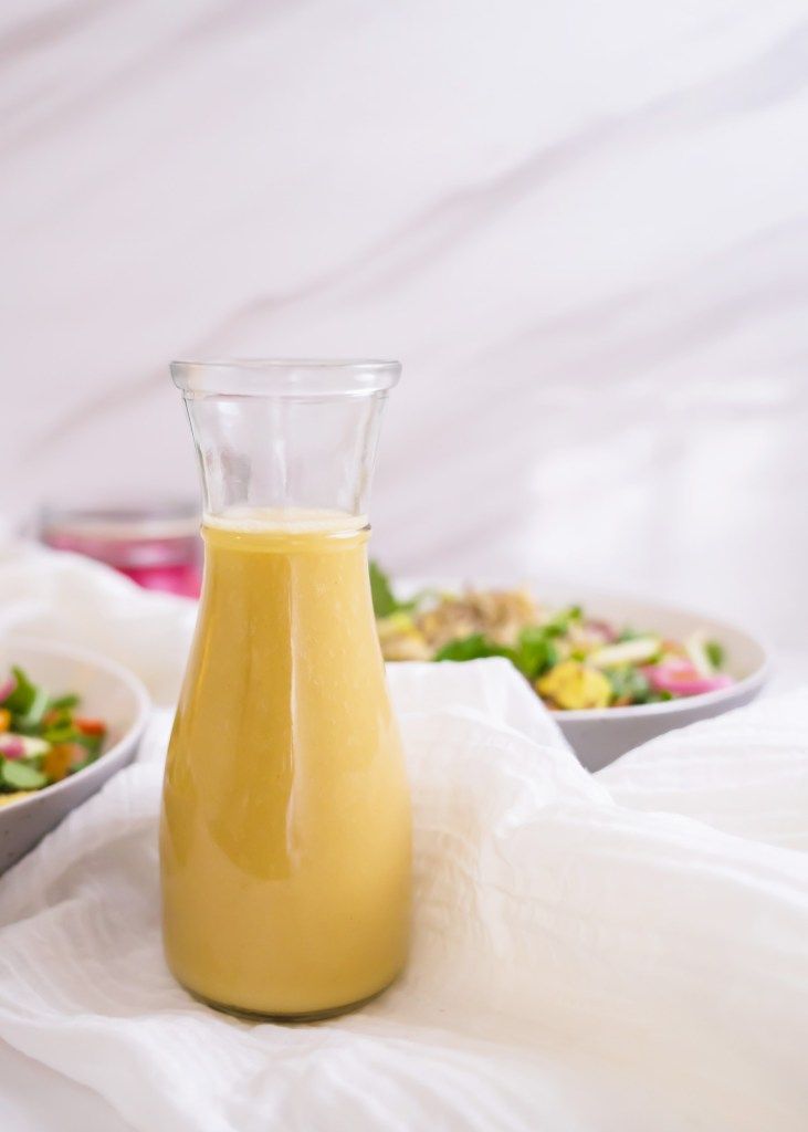 a glass bottle filled with liquid sitting on top of a table next to bowls of food