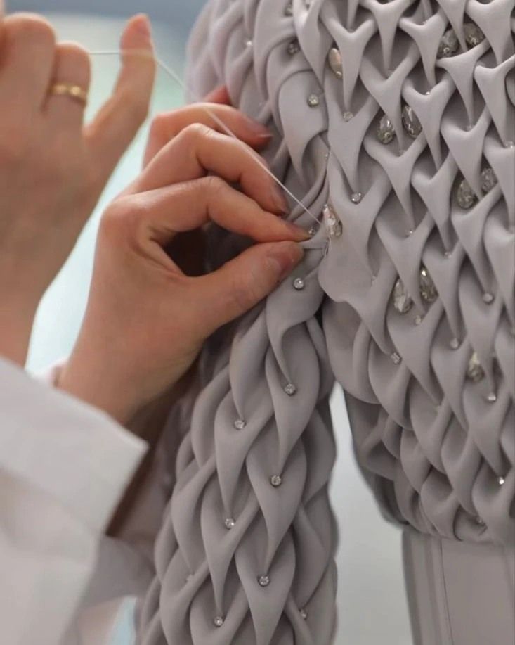 a woman is working on a dress made out of fabric and metal rods with beads