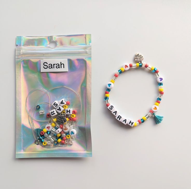 a bracelet with beads and letters on it next to a bag of beads that say sarah