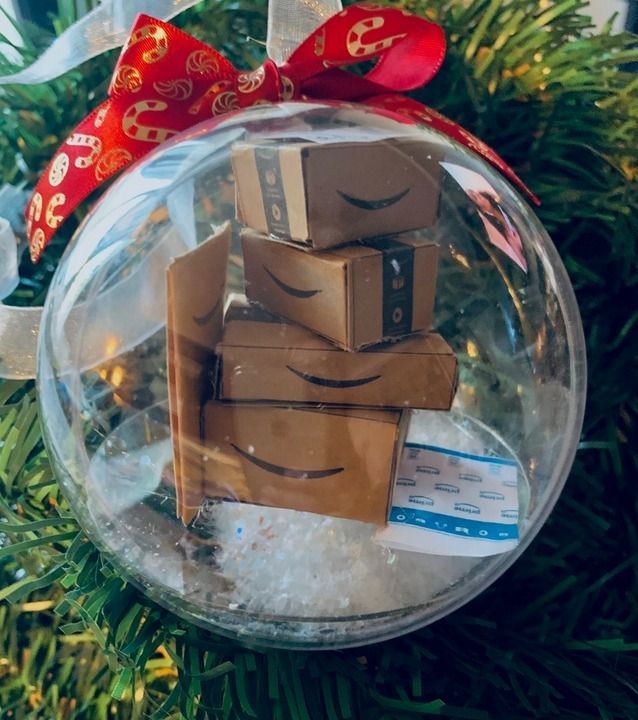 a glass ornament with boxes in it on top of a christmas tree branch