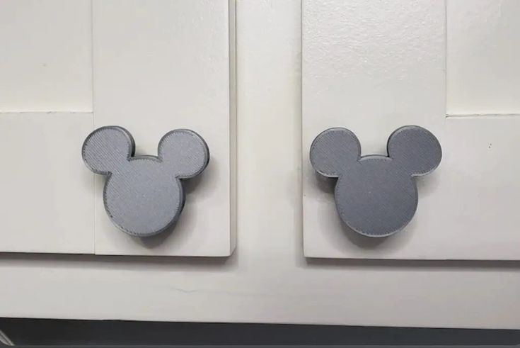 two mickey mouse magnets are attached to the front of a white door with gray trim