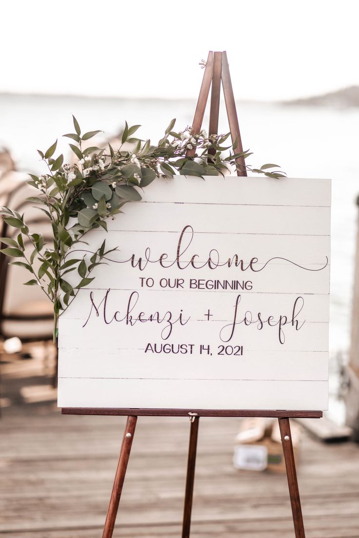 a welcome sign on an easel with greenery