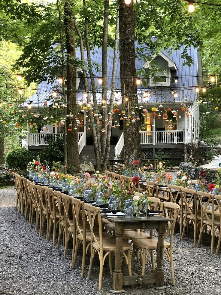 an outdoor dining area with tables and chairs set up in front of a large house