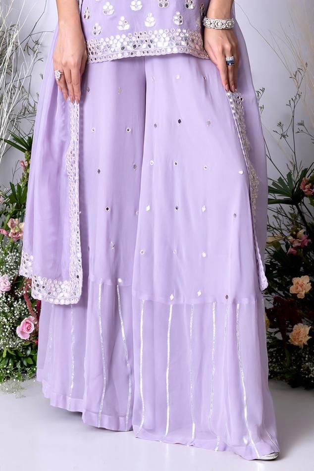 Lilac kurta with all over floral mirror butti embroidery. Paired with a sharara and dupatta with mirror embroidery
Components: 3
Pattern: Hand Embroidery
Type Of Work: Mirror, Floral
Neckline: High Round Neck
Sleeve Type: Sleeveless
Fabric: Viscose Organza
Color: Purple
Other Details: 
Length:
Kurta: 24 inches 
Sharara: 44.5 inches
Weight: 4 kgs
Attached inner lining
Occasion: Sangeet - Aza Fashions Purple Wedding Palazzo Set With Dupatta, Georgette Sharara With Dori Work, Purple Palazzo Set With Dupatta For Wedding, Cutdana Sharara In Georgette, Elegant Purple Sharara With Mirror Work, Purple Semi-stitched Kurta With Mirror Work, Purple Georgette Palazzo Set For Wedding, Elegant Purple Sharara With Cutdana, Purple Georgette Sharara With Cutdana