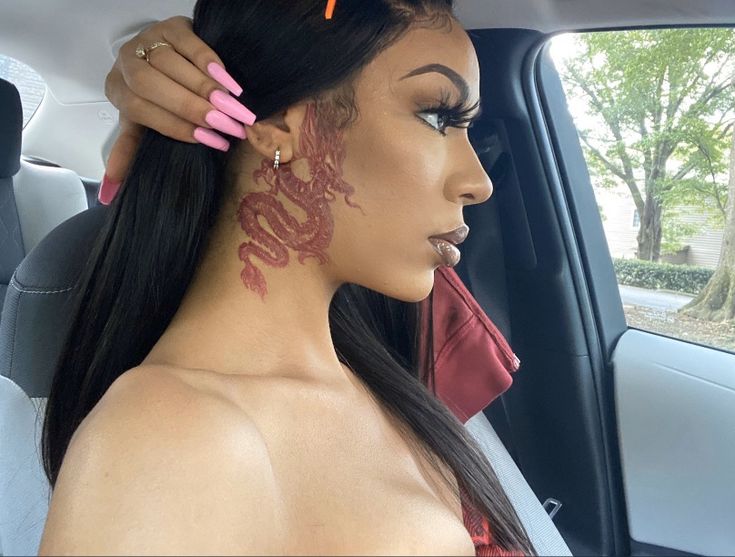 a woman sitting in the back seat of a car with tattoos on her face and neck