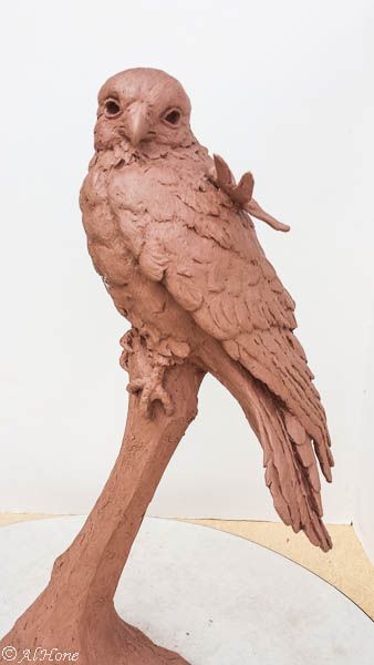 a clay owl sitting on top of a tree branch