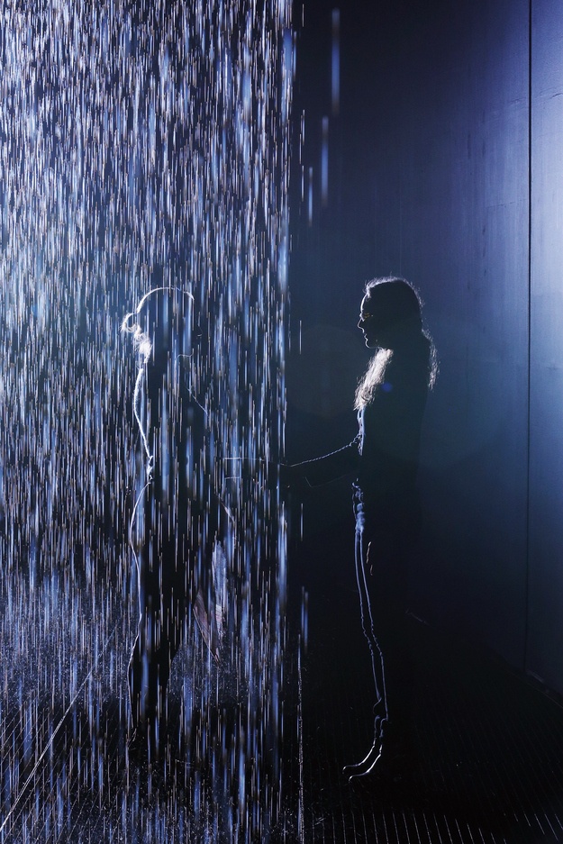 a woman is standing in the rain with her hand on an open umbrella and another person has their arm out