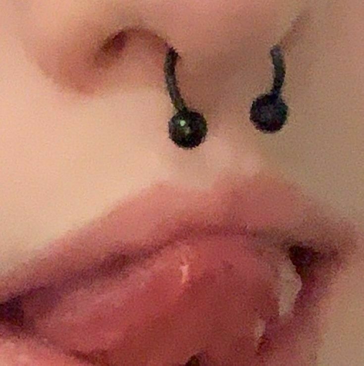 a woman's nose with black earrings on it