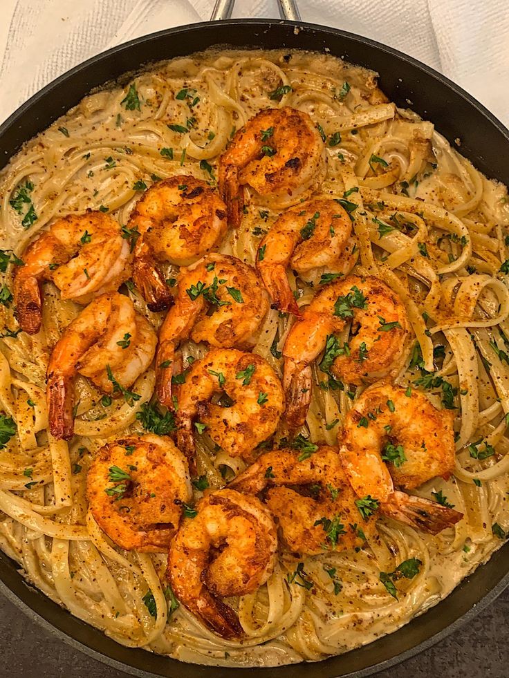 a pan filled with shrimp and pasta on top of a table