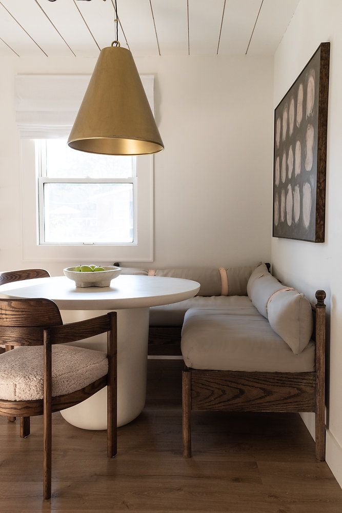 a white table with two chairs and a bench in the corner next to a window