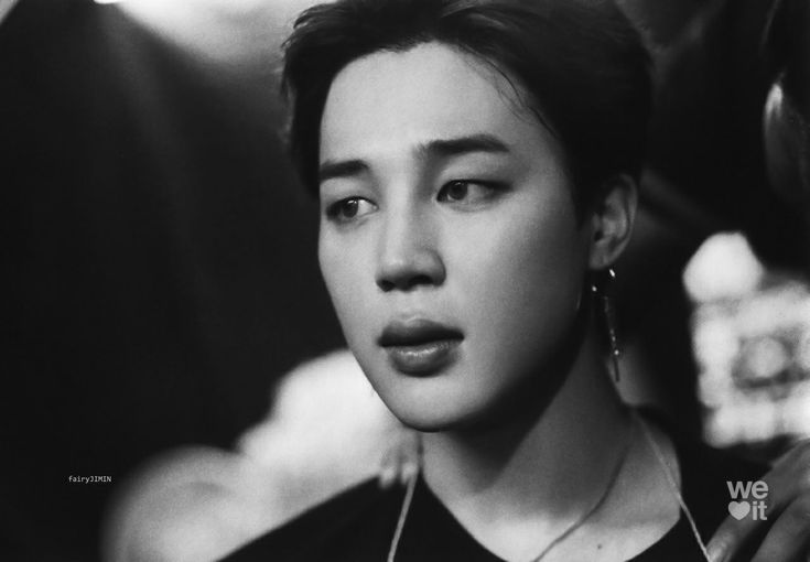 a black and white photo of a young man with ear rings on his ears, looking at the camera