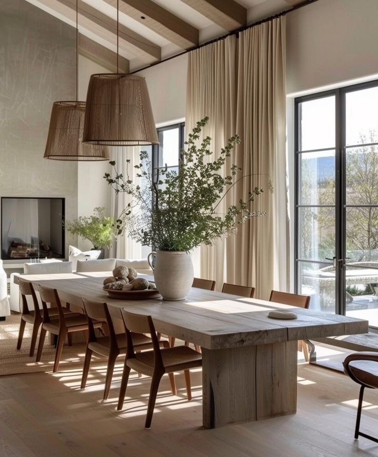 a dining room table and chairs in front of large windows