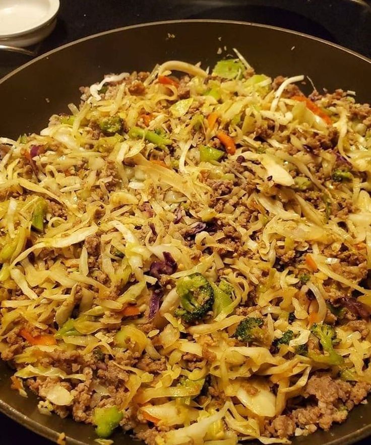 a wok filled with meat and vegetables on top of a stove burner,