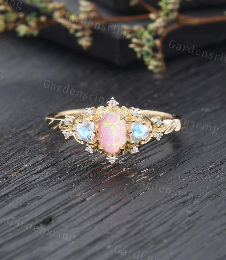 an opal and diamond ring on top of a wooden table