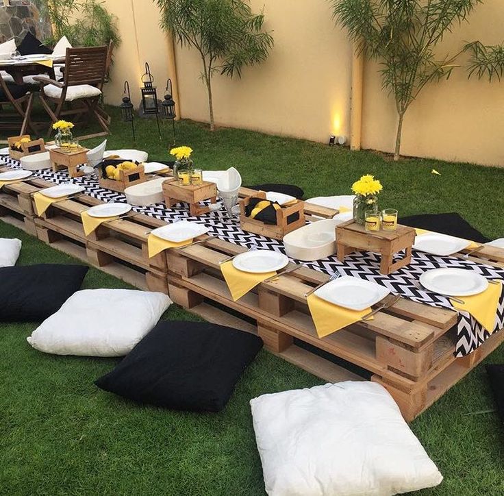 a long table set up with black and white napkins, plates and yellow flowers