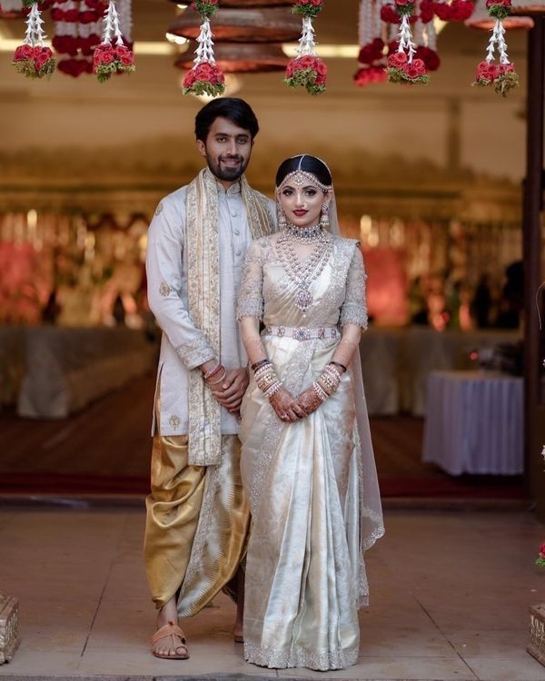 a man and woman standing next to each other in front of a decorated archway with flowers hanging from the ceiling