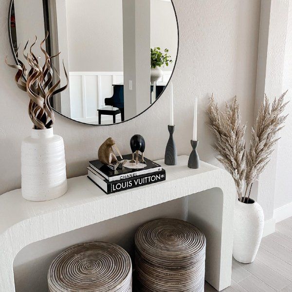 there is a mirror on the wall above two stools in front of a bookshelf