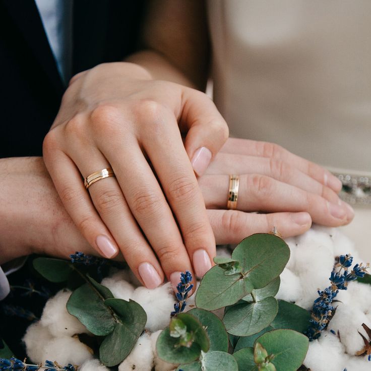 the bride and groom are holding hands with their wedding rings on top of each other