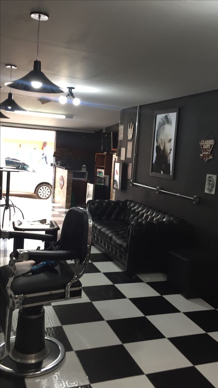 a black and white checkered floor in a room with two leather couches, chairs, and pictures on the wall