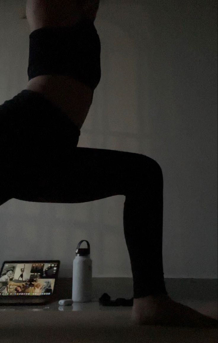 a woman is doing yoga in the dark with her legs spread out and feet crossed