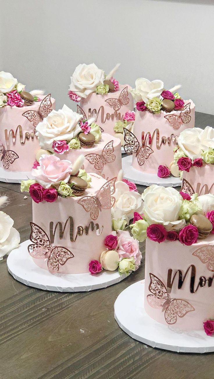 there are many pink and white cakes with flowers on the cake stands, all decorated in different designs