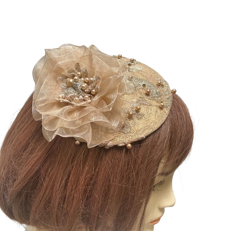 "An antique gold fascinator is covered with intricate beaded gold lace. A champagne colored handmade beaded flower sits on one end and this small elegant hat or gold fascinator is perfect for a formal event. This versatile piece can be worn in many ways. If you choose to have it mounted on a headband it will be fixed on the headband and will be able to be worn on either side of your head. The golden mini hat attaches to your hair with an alligator clip attached to the underside or a satin wrappe Handmade Gold Headpiece With Pinched Crown, Gold Gatsby Headpiece For Party, Handmade Gold Hat For Kentucky Derby, Evening Fascinator With Handmade Flowers And Adjustable Fit, Handmade Flowers Adjustable Fascinator For Evening, Gold Gatsby Headpiece For Vintage Events, Elegant Mini Hat With Handmade Flowers On Headband, Gold Gatsby Headpieces For Evening, Gold Gatsby Evening Headpieces