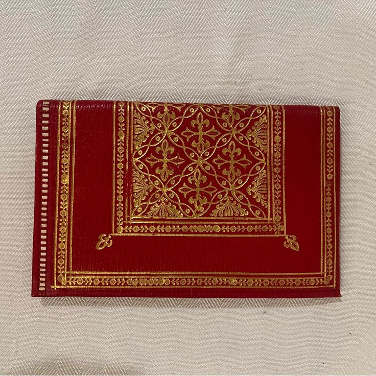 a red and gold book sitting on top of a white cloth