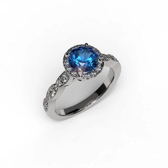 "A dazzling halo set with diamonds that highlights the center round blue sapphire gem of this classic style ring. Majestic and romantic, this Sapphire engagement ring will certainly sweep her off her feet, handmade crafted in 14k white gold, this ring showcases a glorious blue sapphire center stone crowned by smaller round diamonds which also adorn the ring's shank. Polished to a high shine, this elegant ring will become a treasured favorite, this blue sapphire ring is also suitable as an annive Diamond Birthstone Ring With Halo Setting, Cubic Zirconia Birthstone Promise Ring With Halo, Classic Blue Halo Ring With Accent Stones, Elegant Halo Birthstone Ring With Cubic Zirconia, Classic Diamond Birthstone Ring With Halo, Elegant Sapphire Cluster Ring With Halo Design, Classic Diamond Halo Birthstone Ring, Blue Sapphire Halo Ring With Round Cut, Diamond Birthstone Ring With Halo Round Cut