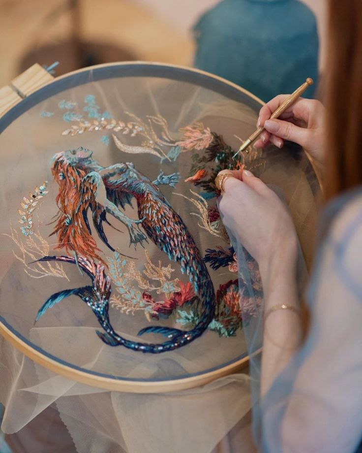 a woman is working on an embroidery project