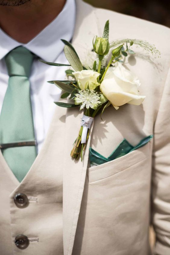 a man wearing a suit and tie with a boutonniere on his lapel