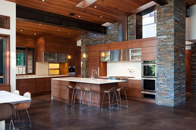 a large kitchen with an island and bar stools in the center, surrounded by wood paneling