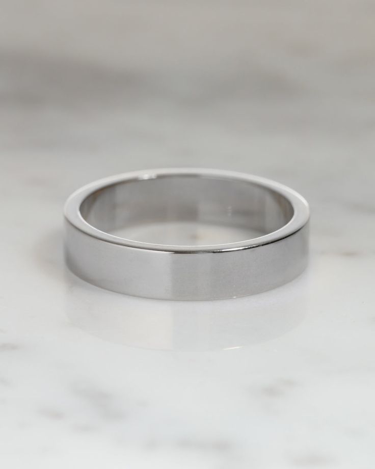 a white gold wedding ring on a marble surface