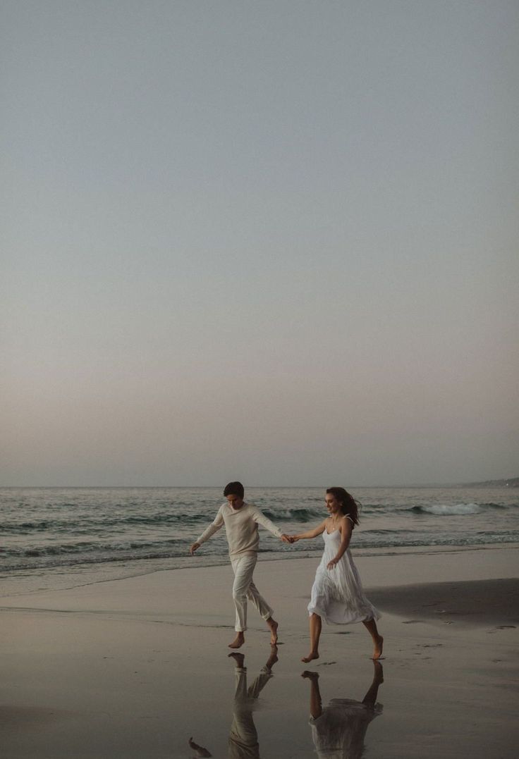 two people walking on the beach holding hands