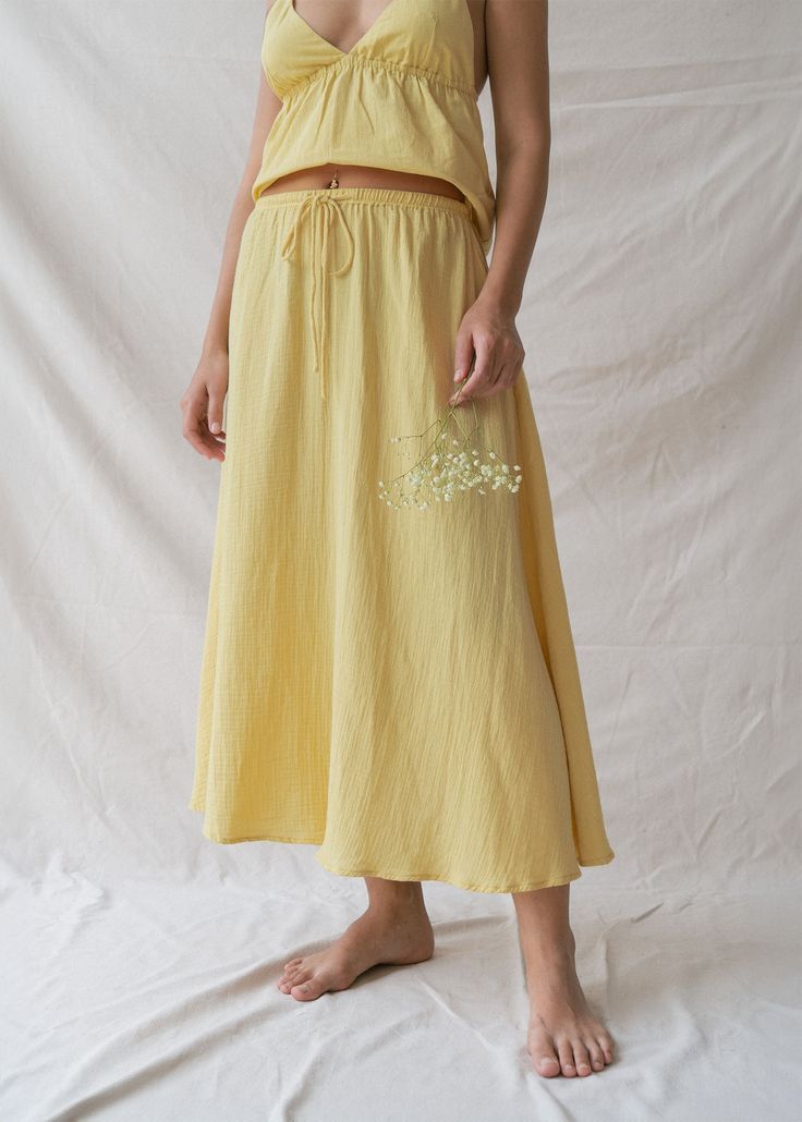 Float through your day in our Mökki Skirt in Sunlight, a pastel yellow that effortlessly captures the essence of summer. Hand-dyed by local artisans, each skirt carries a unique story of craftsmanship and style, ensuring that you wear a piece as one-of-a-kind as you are. This timeless skirt is our favourite for accompanying you from soft mornings to magical evenings. Crafted from the softest Cotton Bubble texture, this simple, classic shape creates the ultimate summer skirt. The flowy, feminine silhouette drapes gracefully, celebrating your natural beauty. An adjustable drawstring and soft elastic waistline ensure a comfortable, custom fit. Effortlessly mix and match through seasonal changes and mood shifts for uncomplicated elegance. Non-see-through fabric provides peace of mind; for opti