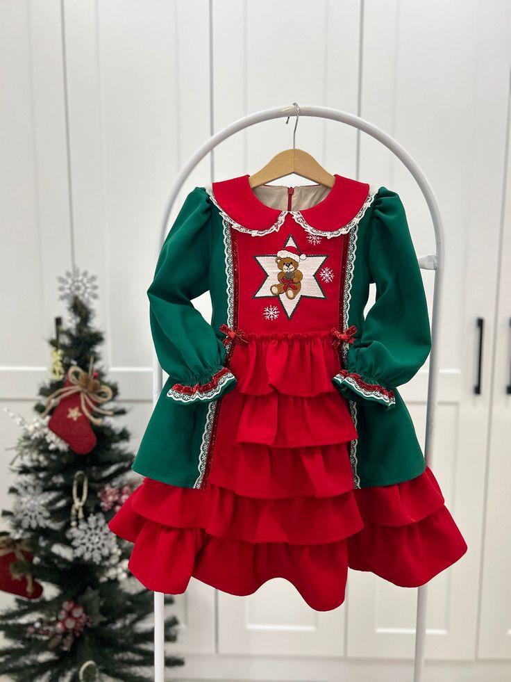 our gorgeous Christmas dress with a lace-trimmed collar and ruffle skirt is a festive choice for the holiday season. the cute and cheerful bear embroidery on the dress bodice is sure to delight your child. A lace-trimmed collar adds a touch of elegance and a vintage charm that complements the playful bear embroidery.  The skirt features ruffles, adding volume and movement to the dress. available size for the dress : 1 to age 8. TURN AROUND TIME 3-4 WEEKS Made to order in Whitby , On Canada If yo Green Christmas Dress For Holiday Dress-up, Green Christmas Holiday Dress For Dress-up, Cute Doll Collar Winter Dress, Cute Winter Dress With Doll Collar, Cute Ruffled Winter Dresses, Long Sleeve Dresses With Ruffles For Winter, Cute Long Sleeve Holiday Dress, Green Christmas Holiday Dress, Cute Long Sleeve Festive Dresses