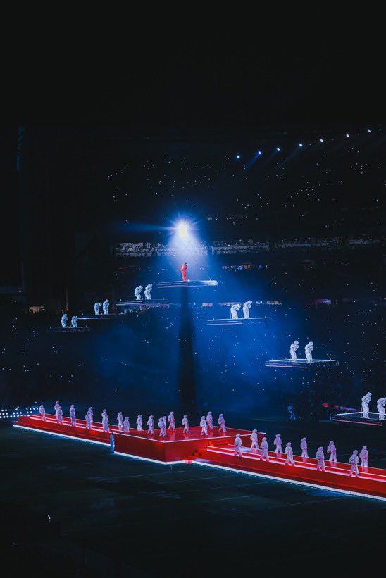 the stage is lit up with red and white lights as people are standing on it