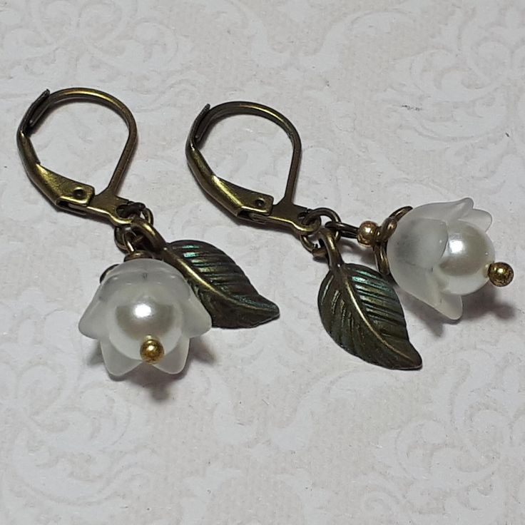 LILY OF THE VALLEY EARRINGS ▪️▪️▪️▪️▪️▪️▪️️▪️▪️▪️▪️▪️▪️ These dainty flower earrings are made with cute white Lucite flowers and elegant white glass pearls. An individual antique bronze leaf and lever back hooks finish them. They are very light weight so easy on the ears and perfect for everyday wear yet pretty enough for special occasions, bridesmaids or as a cute gift.  💜MATERIALS *Antique Bronze Findings *Lucite Flowers *White Glass Pearls   💜DIMENSIONS *1.8cm drop ▪️▪️▪️▪️▪️▪️▪️️▪️▪️▪️▪️▪️ Vintage White Flower Drop Earrings, Vintage White Dangle Flower Earrings, White Flower Earrings, Red Flower Earrings, Purple Lily, White Flower Earring, White Pearl Earrings, Pink Gift Box, White Pearl Earring